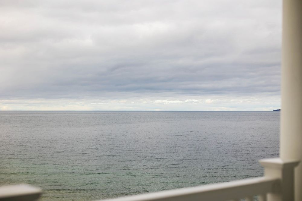 Serene overcast ocean view from balcony with calm gray waters stretching to horizon.