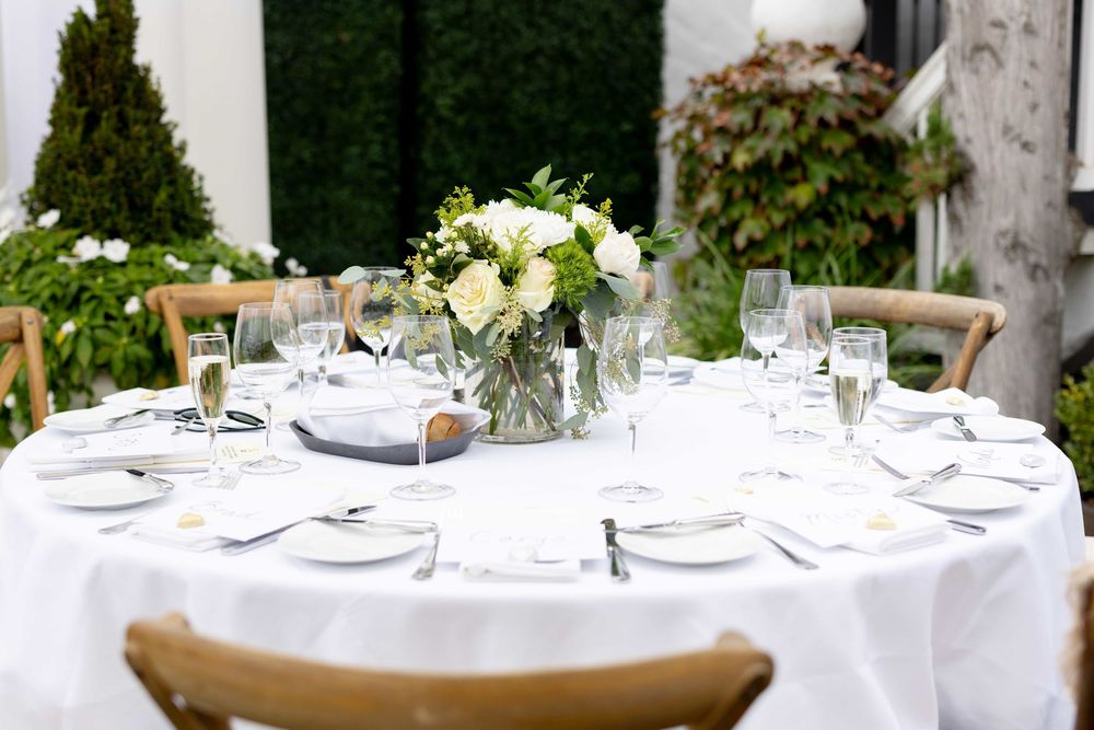 Beautifully set outdoor wedding reception table with white linens and floral centerpiece.