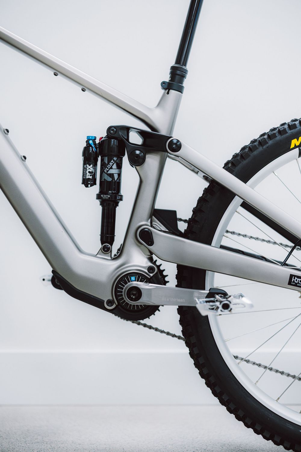 Side view of a silver full-suspension electric mountain bike frame with Fox rear shock.