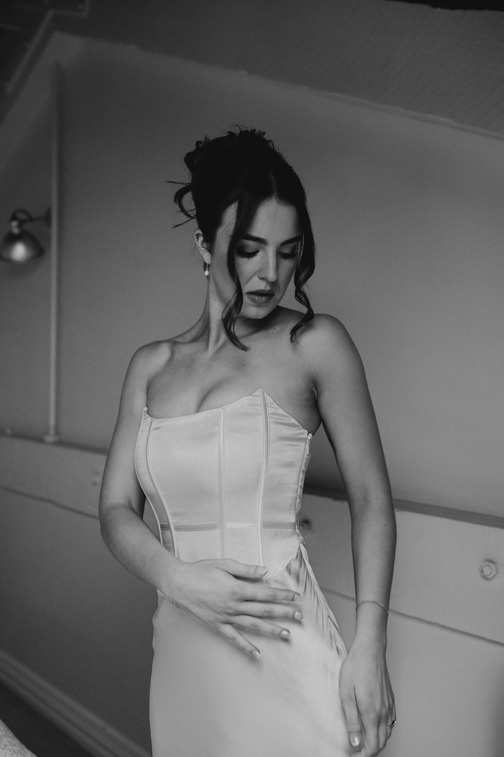 Elegant bride in strapless corset wedding gown posing in black and white portrait.