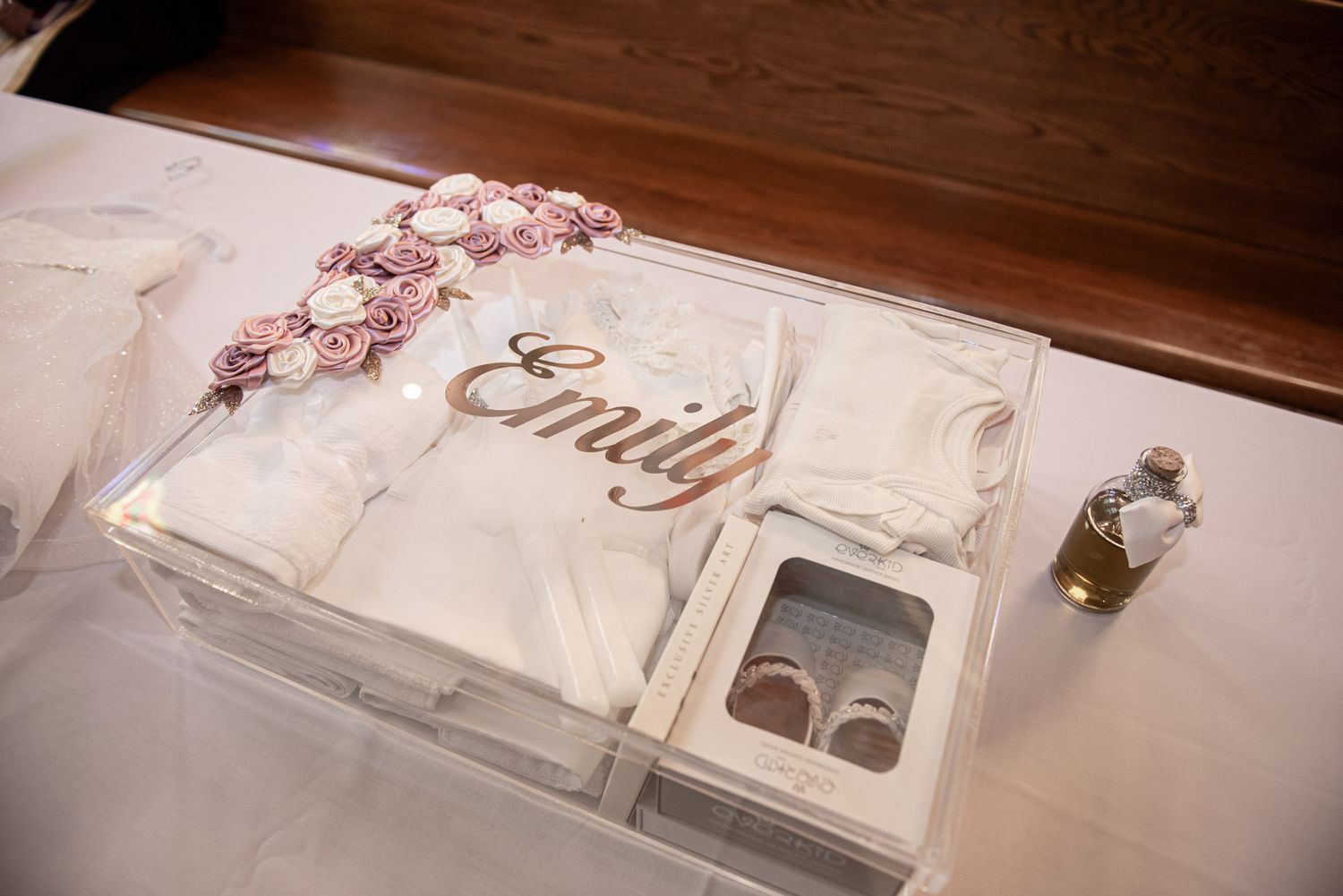 Personalized baby baptism gift box named Emily with white outfit, shoes, and floral decorations.