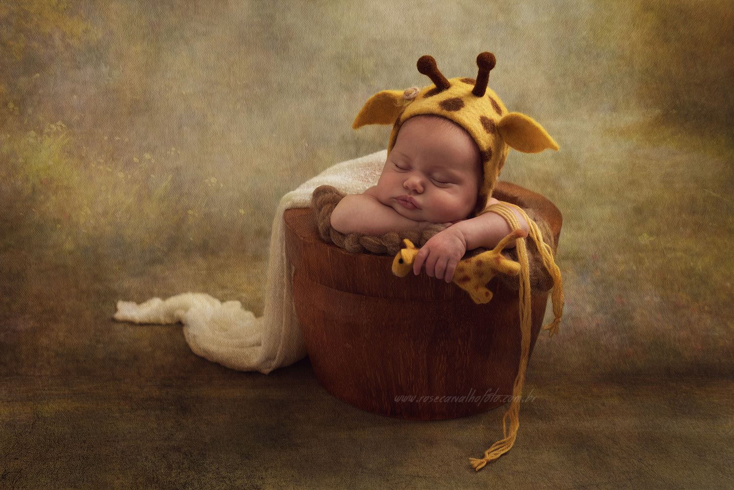 Ensaio newborn com bebê usando touca de girafa exclusiva, deitado de forma angelical em estúdio por Rose Carvalho.