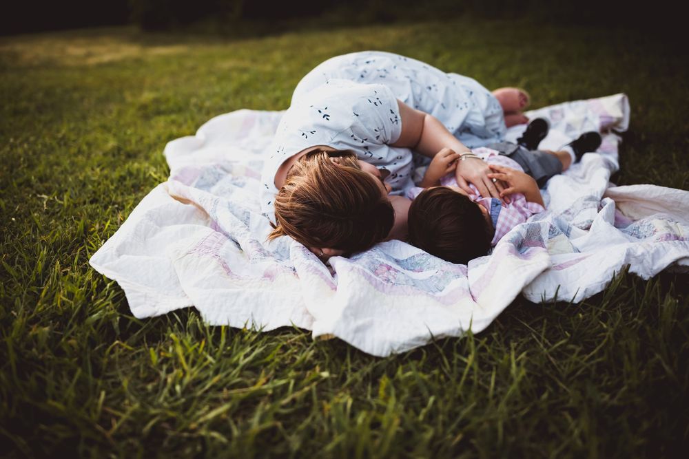 A series of connected photos showing someone lying peacefully on a white blanket in green grass.