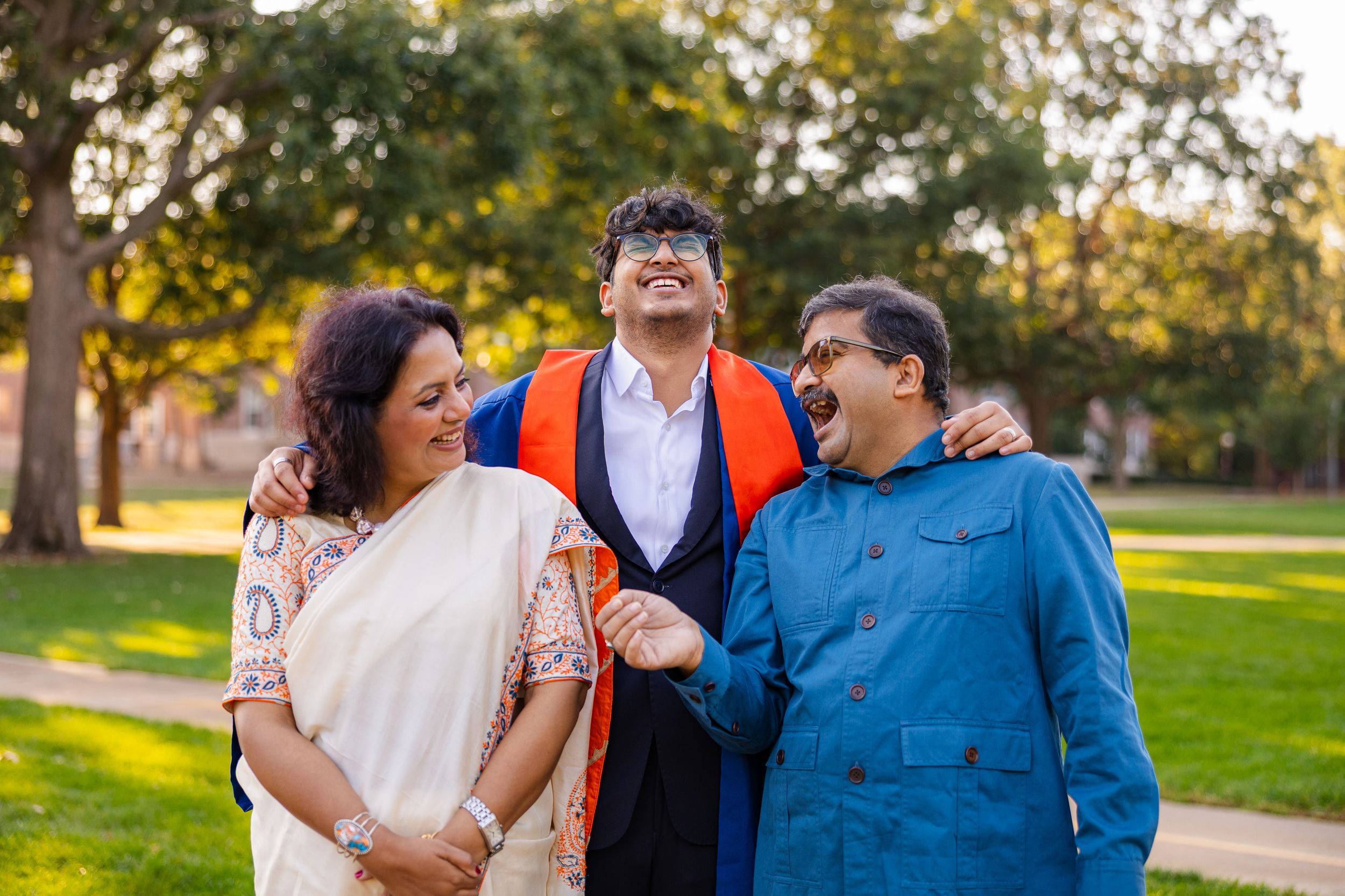 Graduating student's family laughing together at the UIUC Main Quad at golden hour