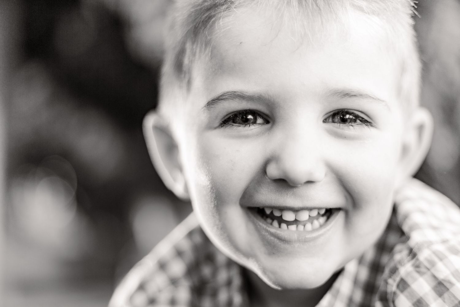 A series of black and white portraits showing joyful expressions and genuine smiles.