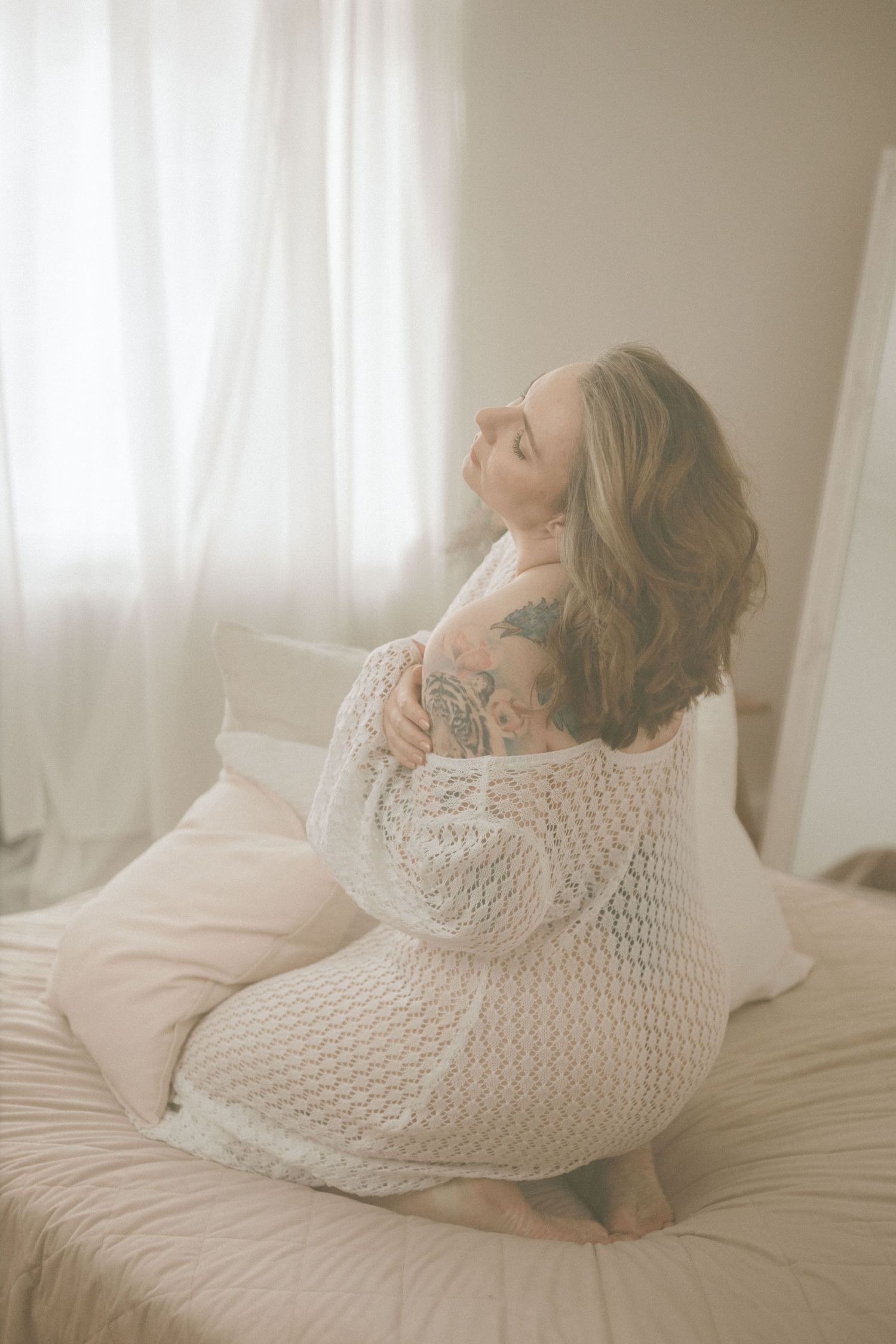 Sinnliches Portrait einer kniehenden Frau im weißen Strickkleid beim Boudoirfotoshooting im hellen Ambiente