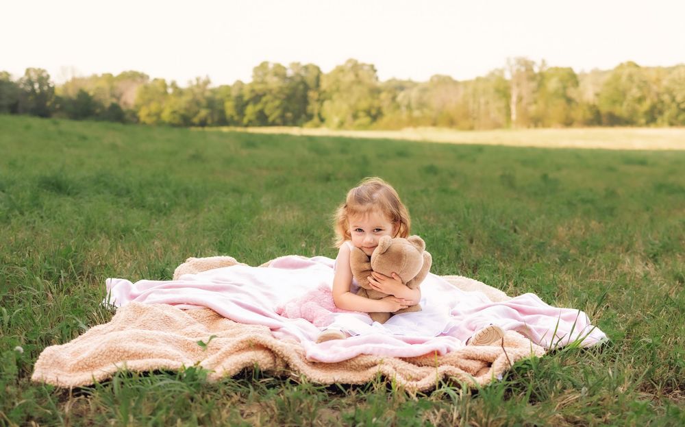 A series of outdoor photos showing a blanket laid out in a grassy field during golden hour lighting.