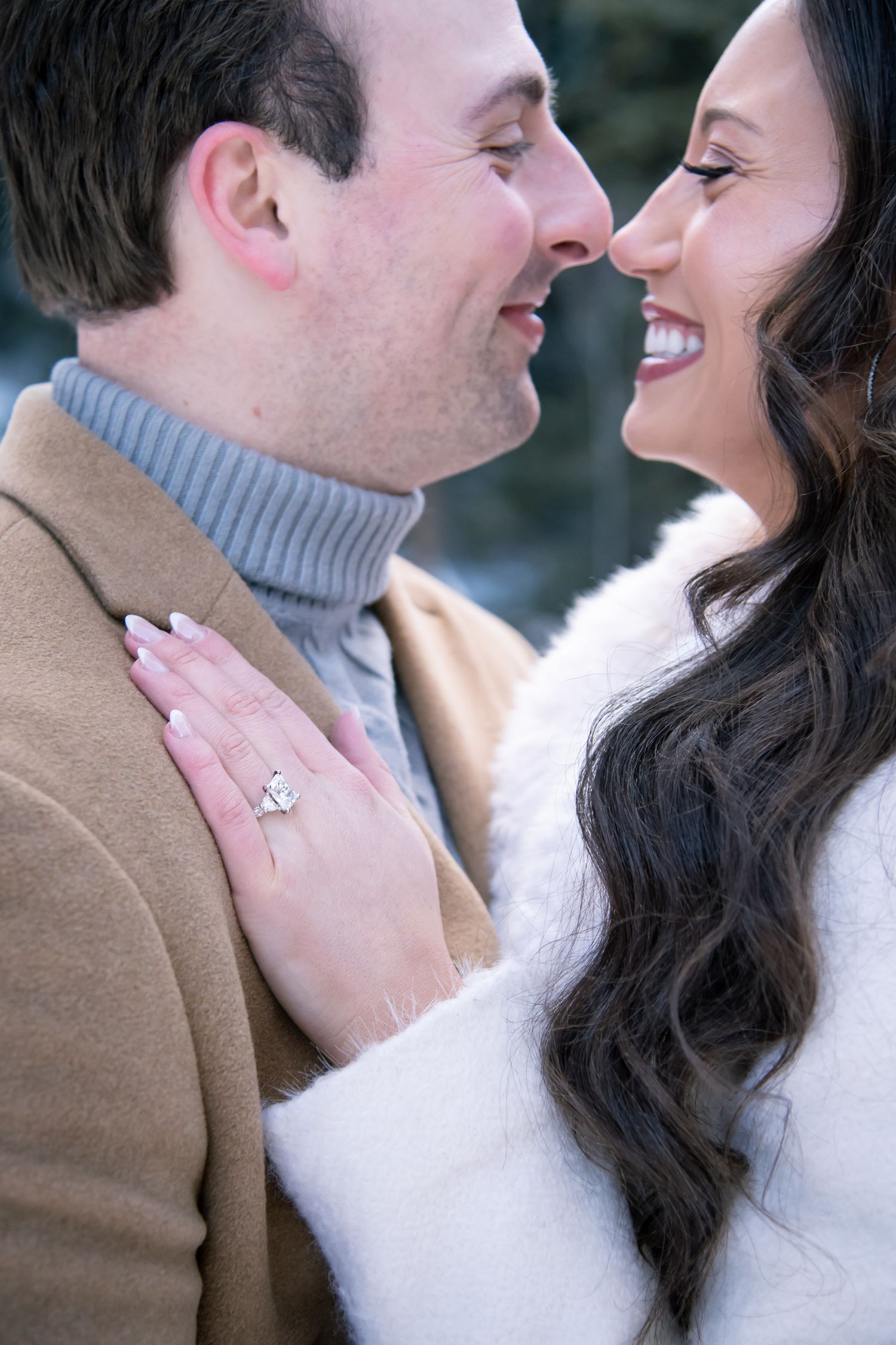 Chic couple smiles facing each other for Vail Colorado winter engagement photo session.
