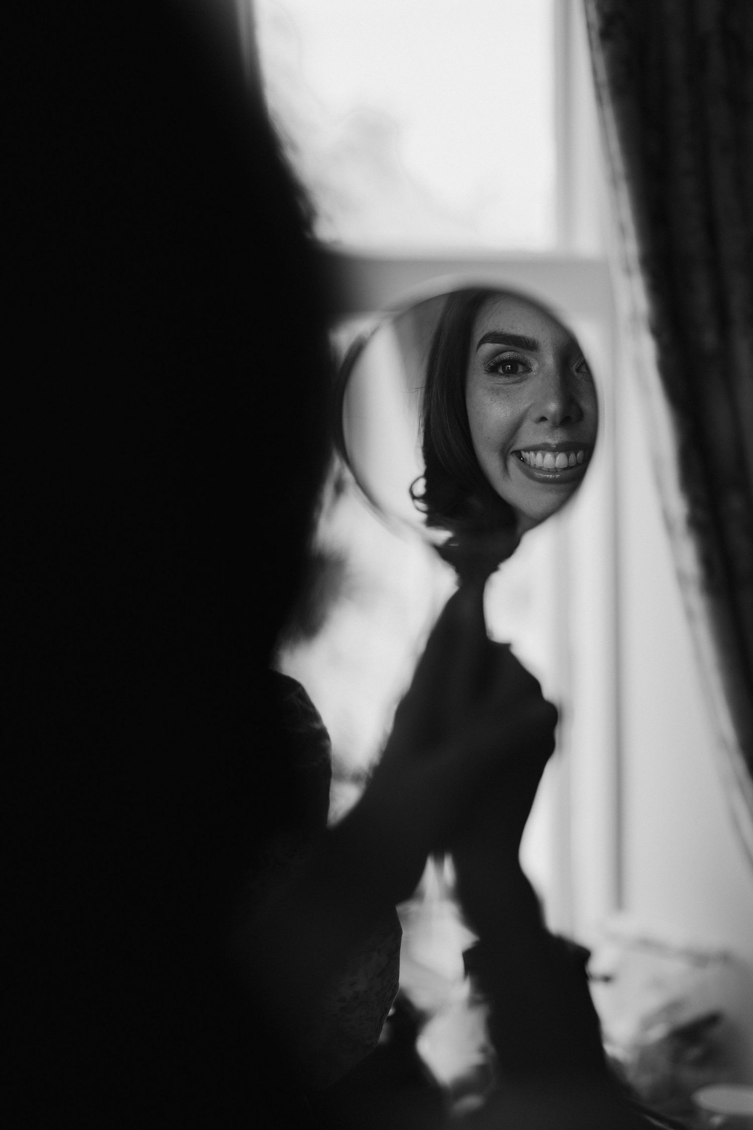 bride smiling back at herself in hand mirror at dewsall court in herefordshire
