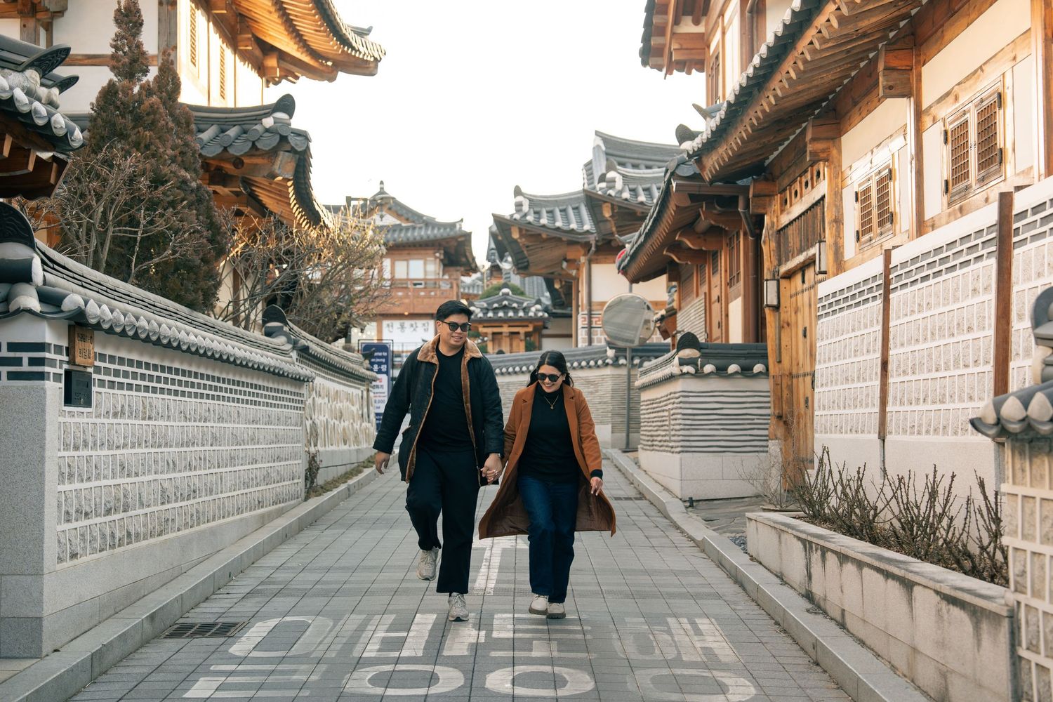 People walking along traditional stone pathways in Bukchon Hanok Village, Seoul, with traditional Korean architecture.