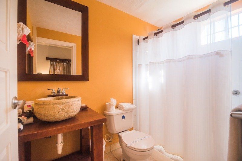 Modern bathroom with orange walls featuring vessel sink and white shower curtain.