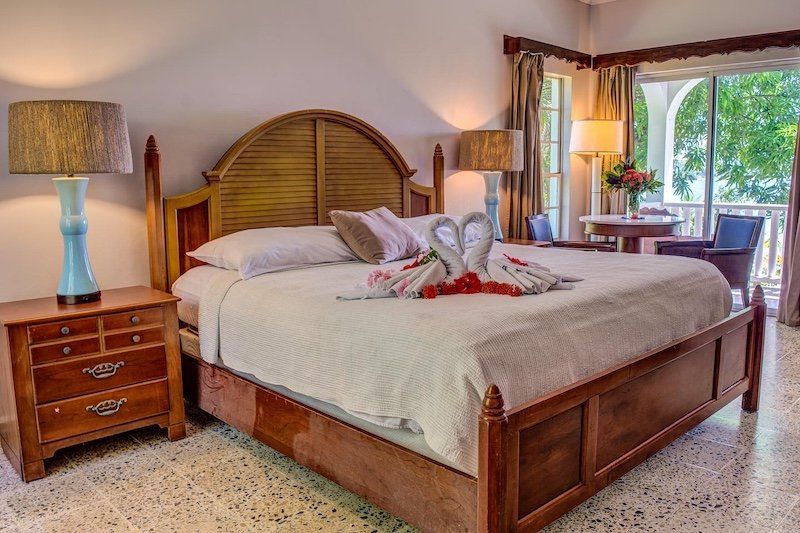Elegant bedroom with wooden furniture and decorative towel arrangement on bed.