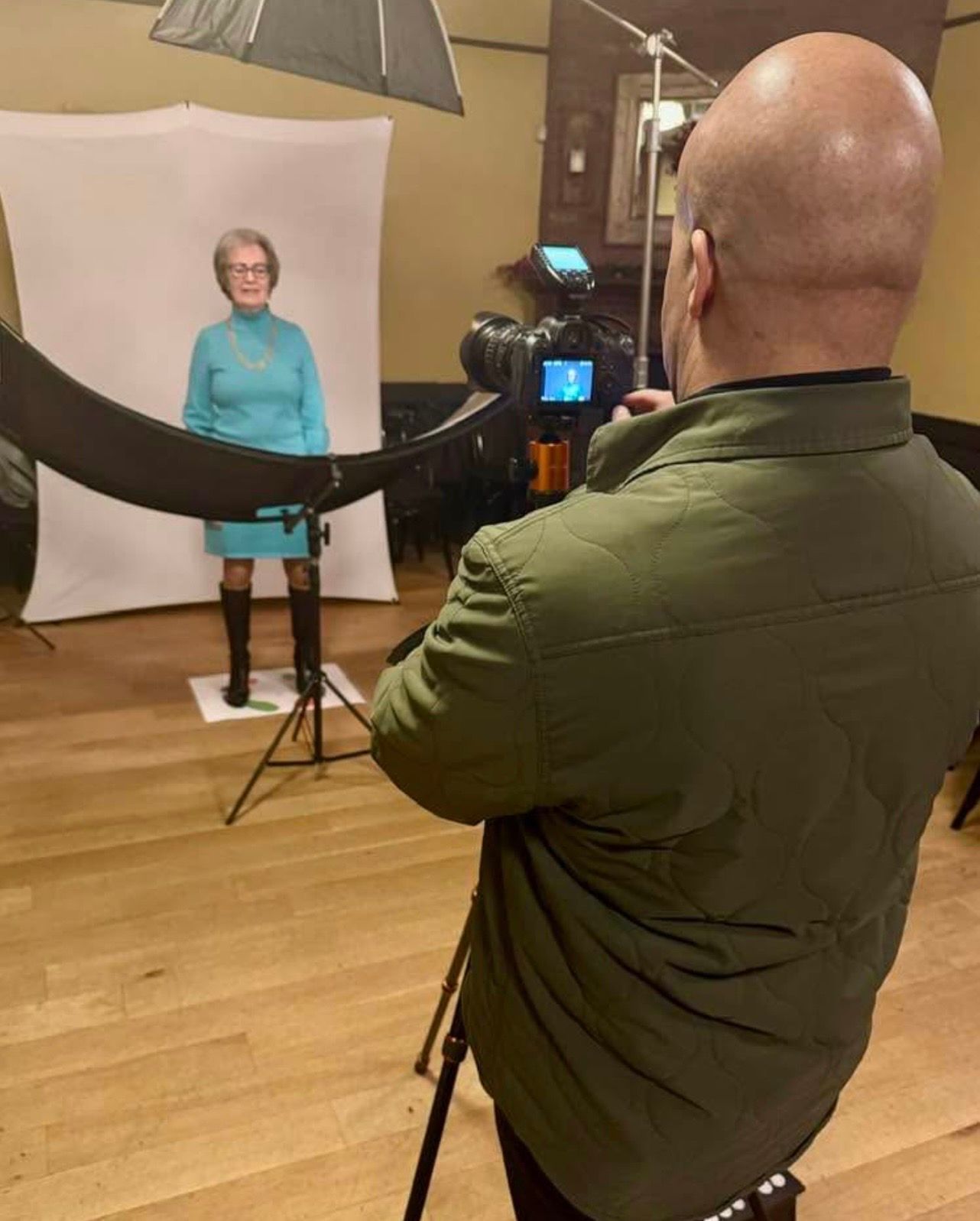A professional business headshot session in progress with a photographer and client using floor posing guides.