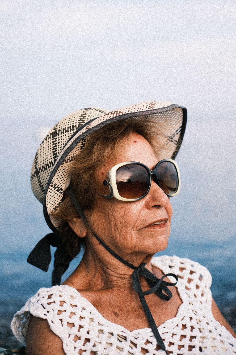 A person in sunglasses and a patterned hat poses outdoors against a cloudy sky in a series of similar shots.