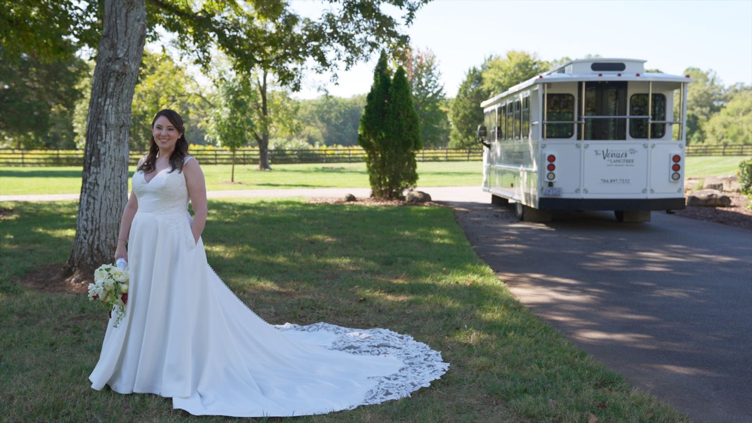 A scenic outdoor wedding venue with lush green trees, a white gazebo, and a winding path through the grass.