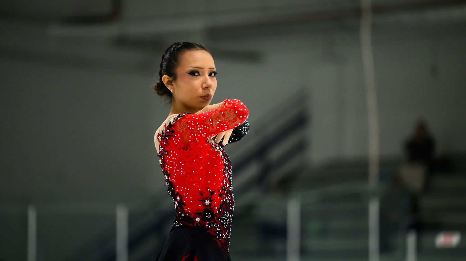 Two figure skaters perform a dramatic sliding move together on ice during a skating routine.