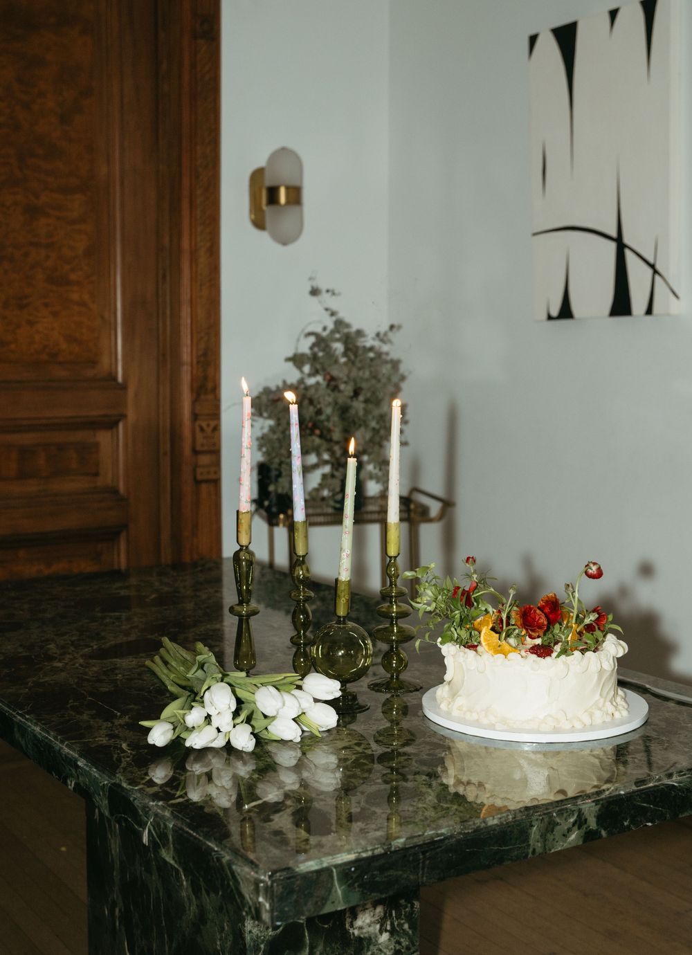 A series of elegant white candles and floral arrangements displayed on a dark marble surface for a special celebration.