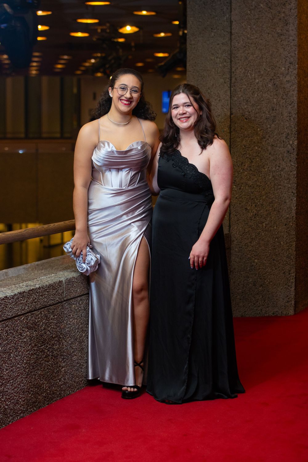 Two people in formal evening wear pose together on a red carpet at an elegant event.