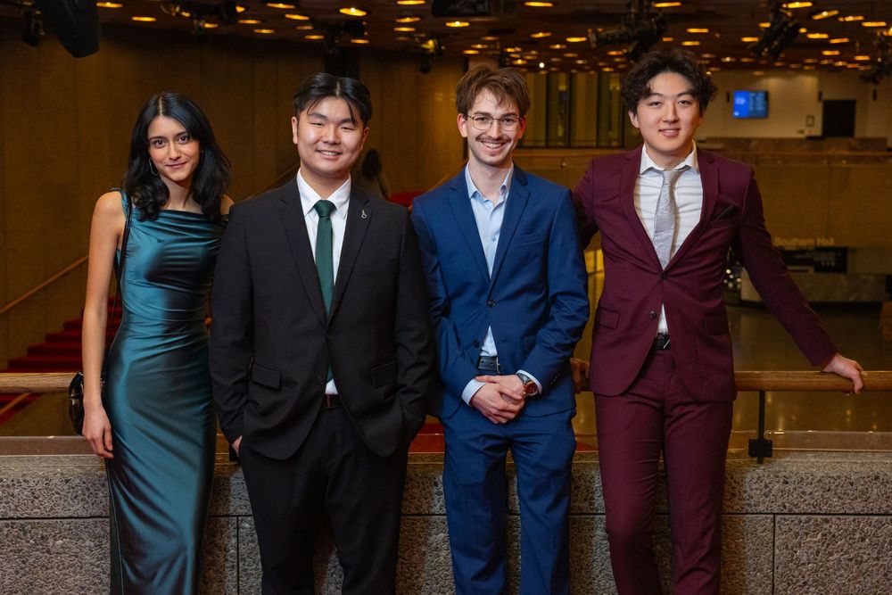 A group of formally dressed teens posing together at what appears to be a school dance or prom event.