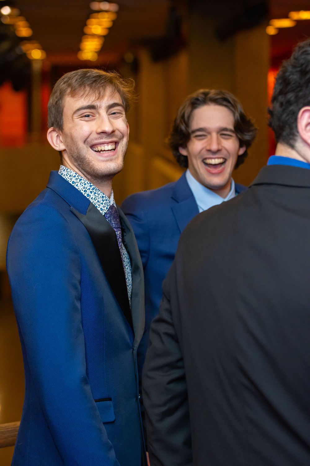 Group of young people in formal attire smiling and socializing at an event.