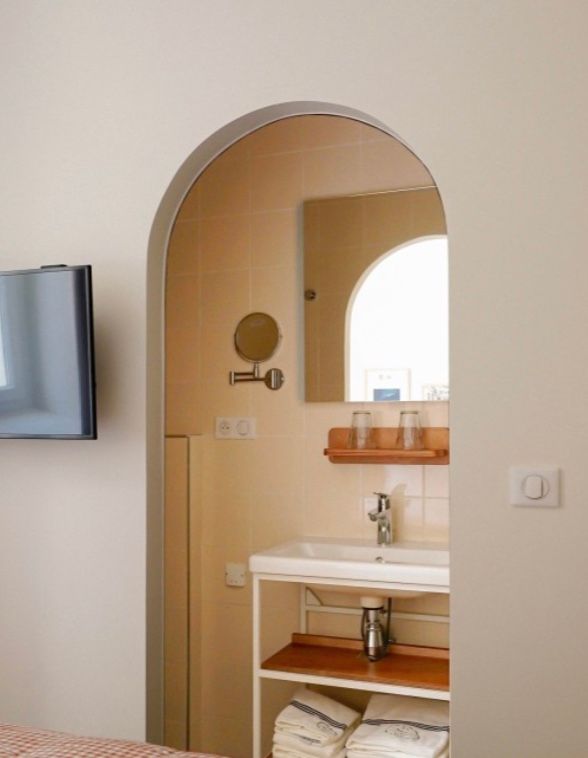 Arched doorway leads into a bright bathroom with beige walls and modern fixtures.