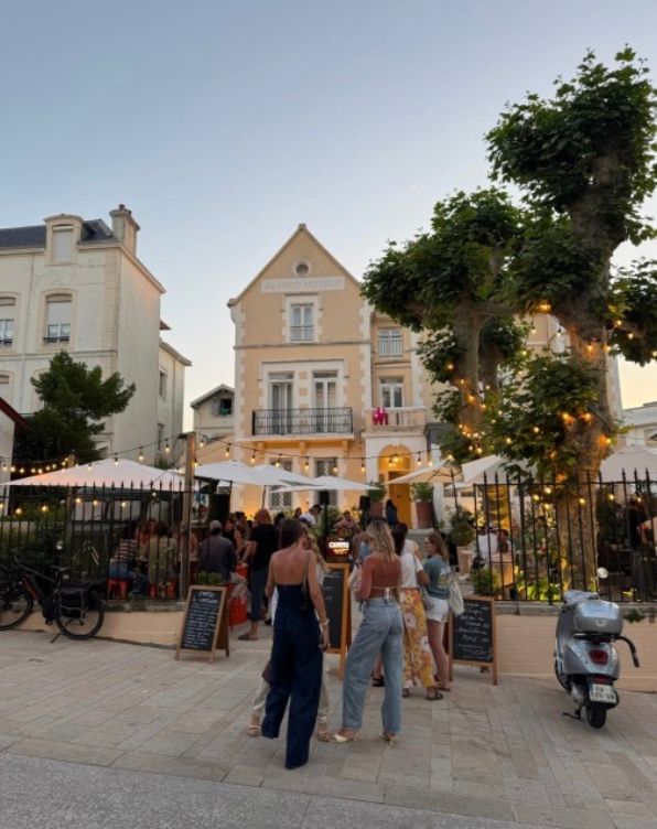 Charming pedestrian street in a French coastal town at dusk with restaurants and shops lining the walkway.