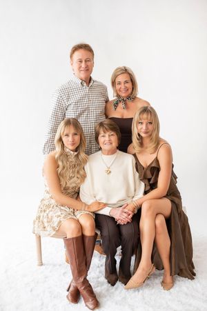 A family of five poses for a professional portrait, with two standing and three seated against a white background.