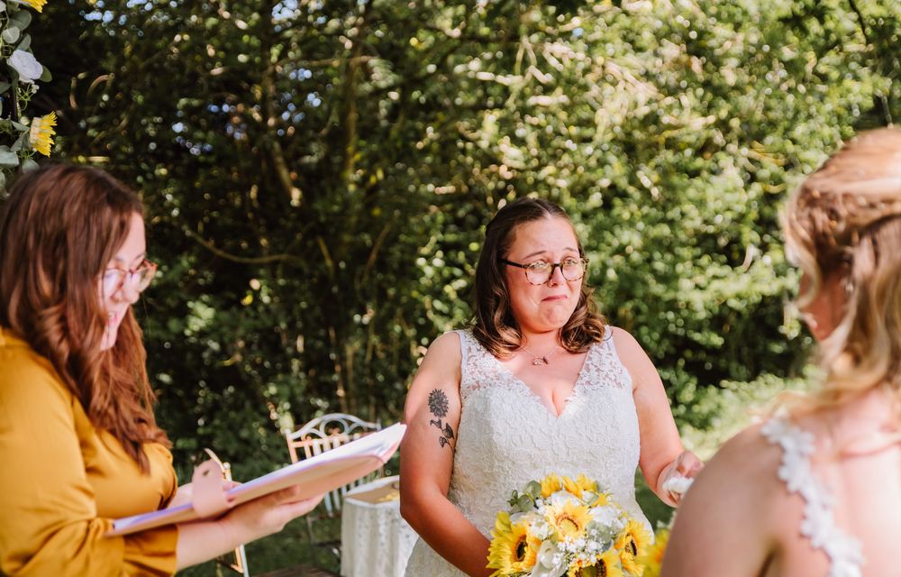 Bride cries at Gaggle of Geese Tipi outdoor wedding venue in Dorset. LGBTQ+ wedding photographer Dorset. Sunflower wedding bouquet and sunfl