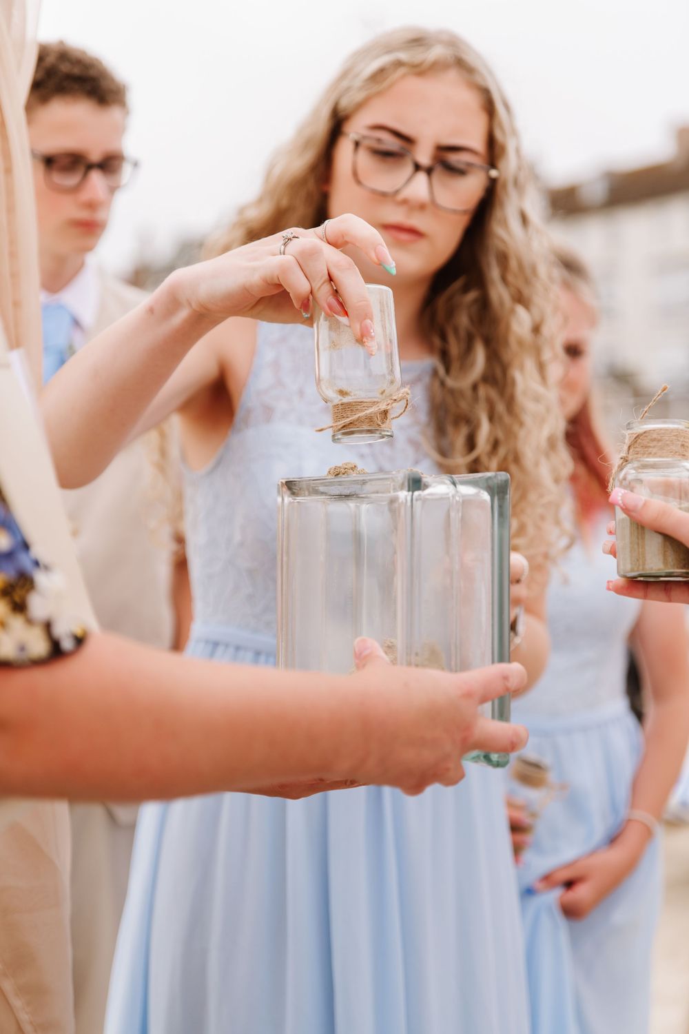 UK beach wedding on Weymouth Beach with Ceremonies by Laura Bell completing sand pouring. Sunflower bouquet and blue bridesmaid dress