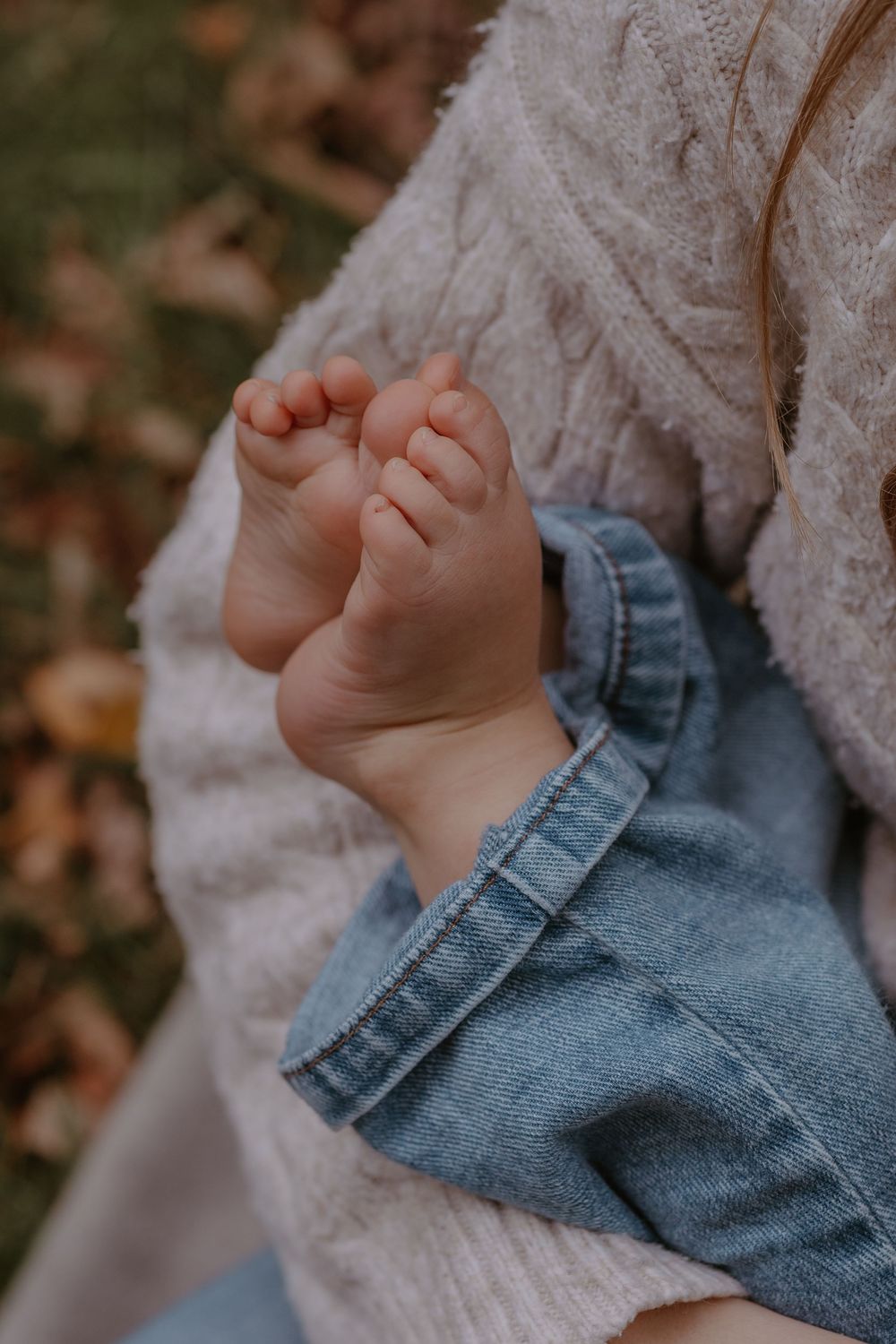 Close-up of tiny baby feet in denim against white knit fabric.