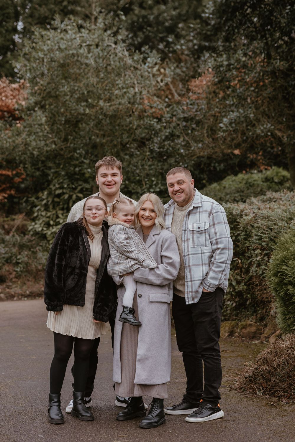 Family group posing together on a path surrounded by autumn trees.