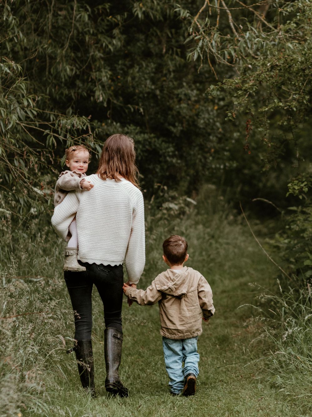 People walking together on a nature trail surrounded by green foliage.