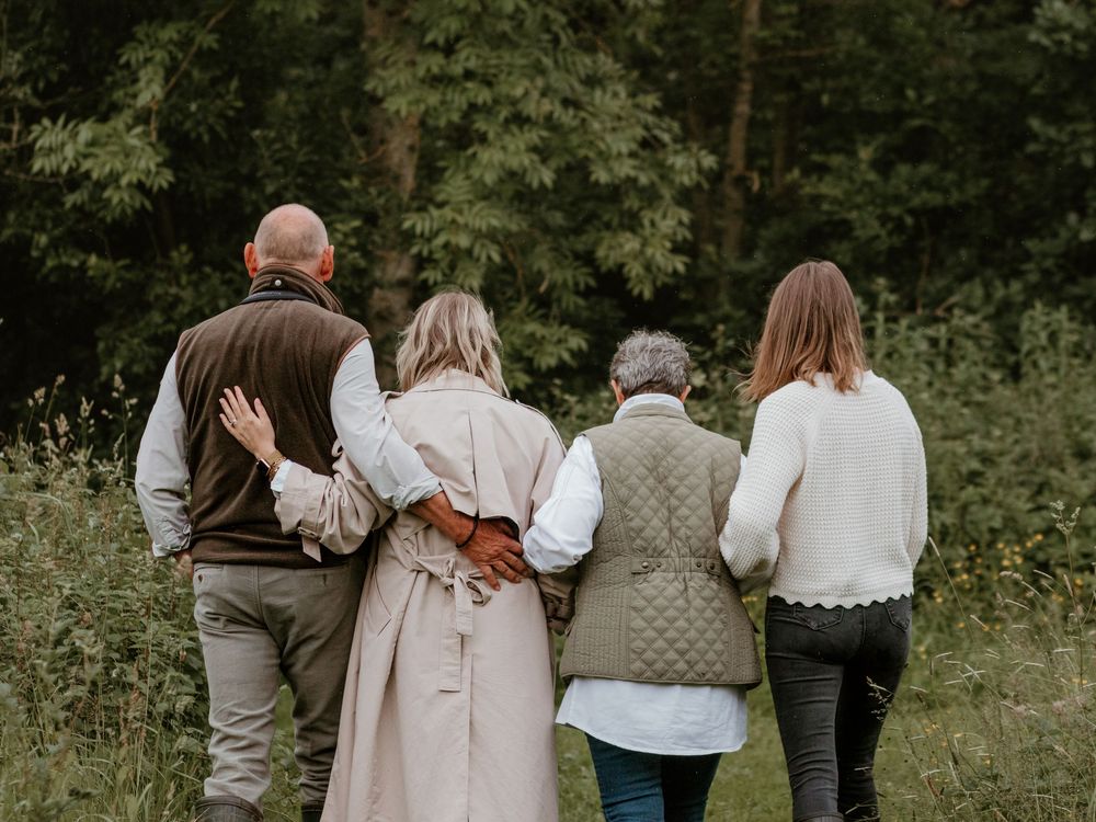 Grown up daughters walking side by side with their elder parents.