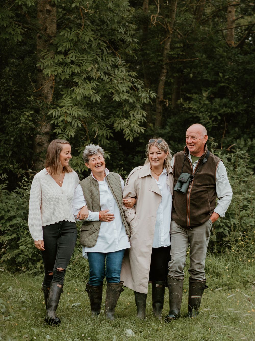 Mum, Dad and their two daughters walk arm in arm in the forest sharing a moment of joy and laughter.