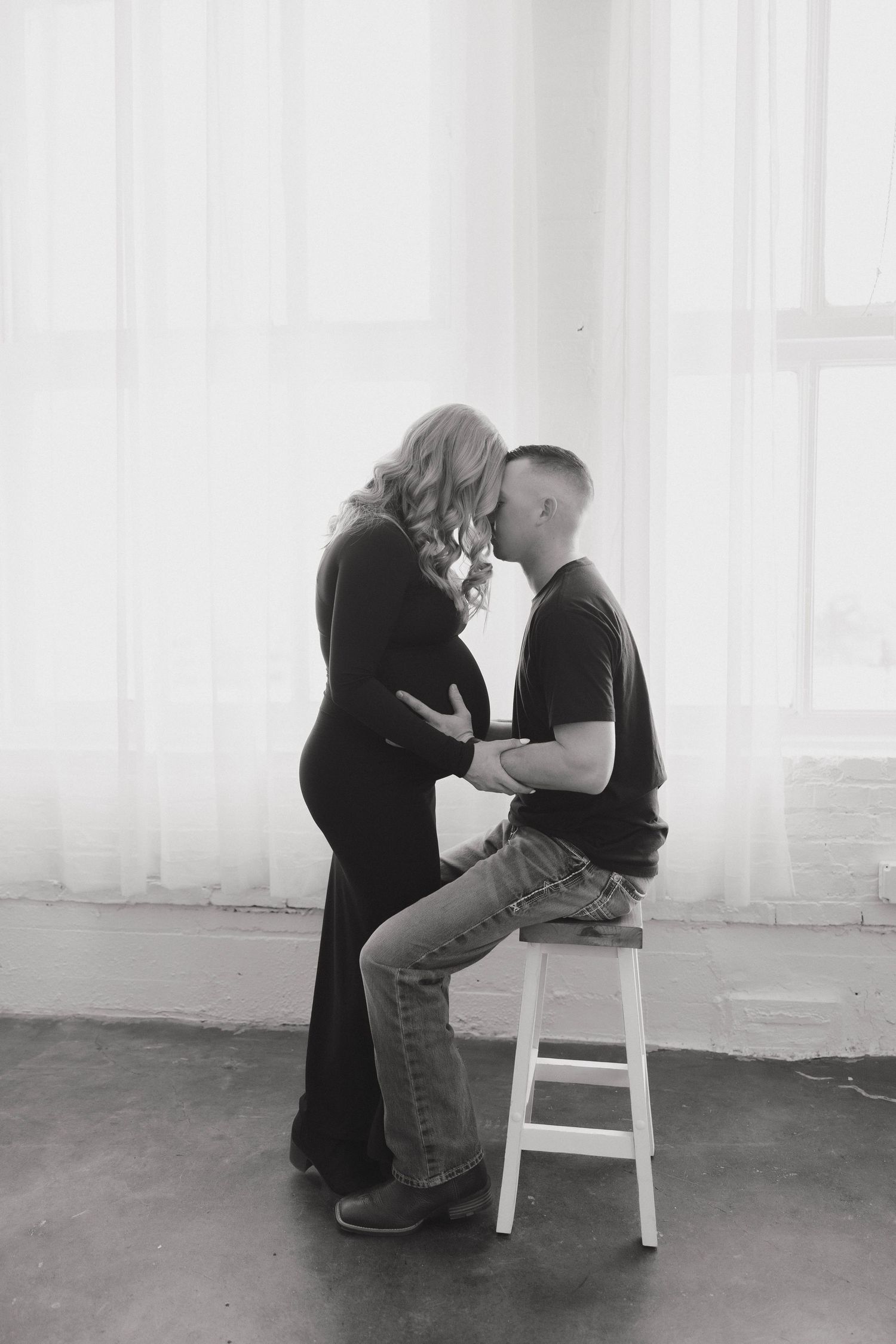 A series of black and white artistic photographs showing a couple sharing intimate moments near a white stool.