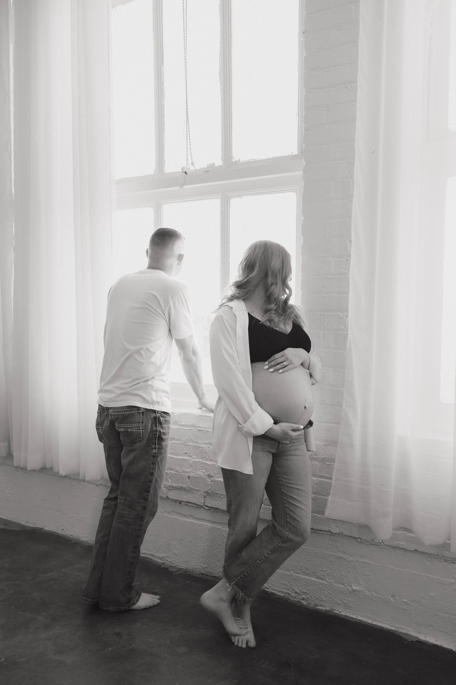 Multiple intimate poses of a couple in black and white against a bright window backdrop.