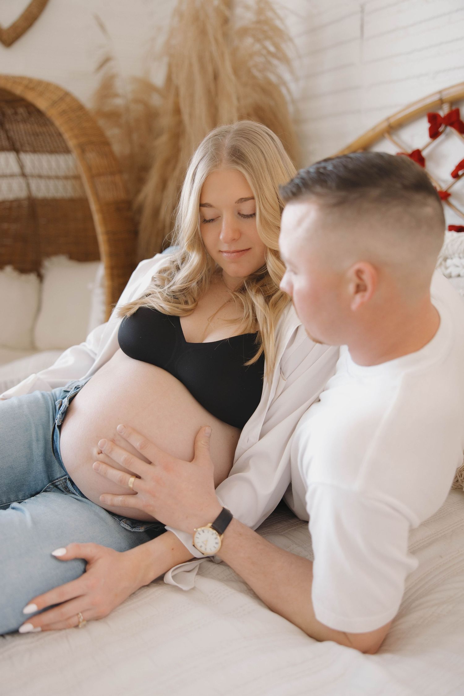 Intimate maternity photoshoot with couple lying together on floor surrounded by neutral decor.
