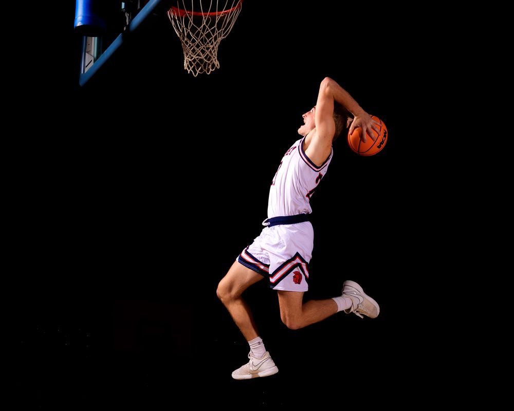 Hershey High School basketball player jumping for a slam dunk against a black background during Media Day action portraits.