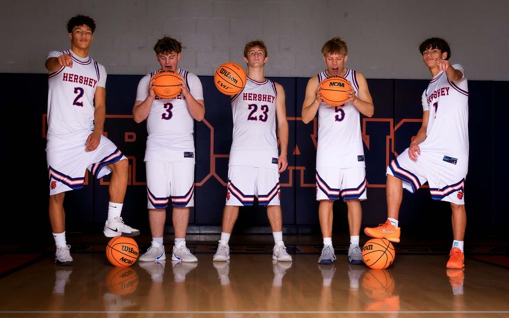 Group portrait of Hershey High School boys basketball seniors posing together with creative lighting for Media Day.