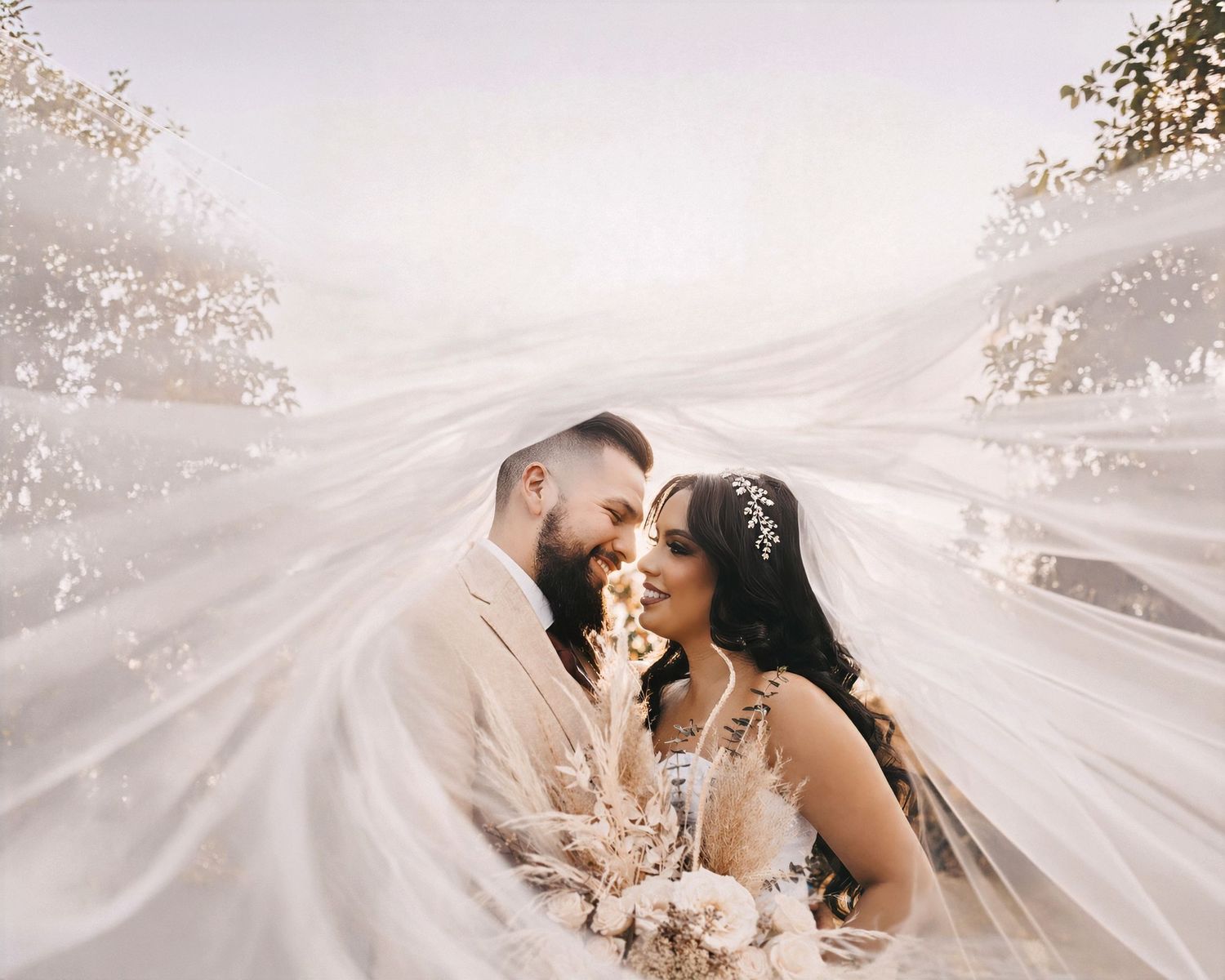 gorgeous sunset behind a bride and groom looking at each other under the veil