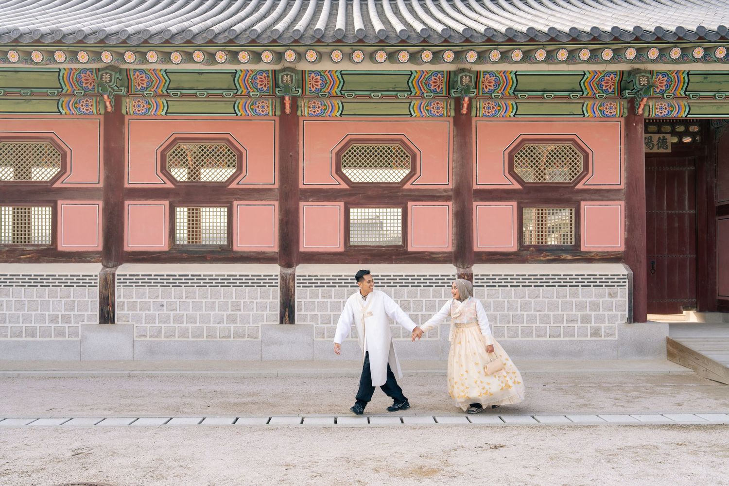 Traditional Korean palace buildings with curved roofs and ornate architectural details line a courtyard at Gyeongbokgung Palace.