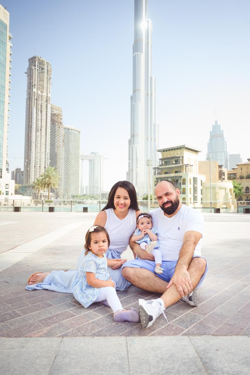 A couple poses together against a cityscape backdrop in Dubai with the iconic Burj Khalifa tower visible.