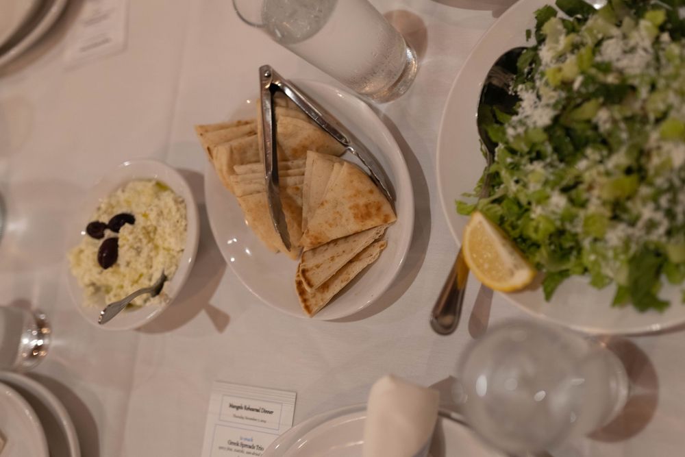 An elegant dinner table setting with multiple plates of food and drinks arranged on a white tablecloth.
