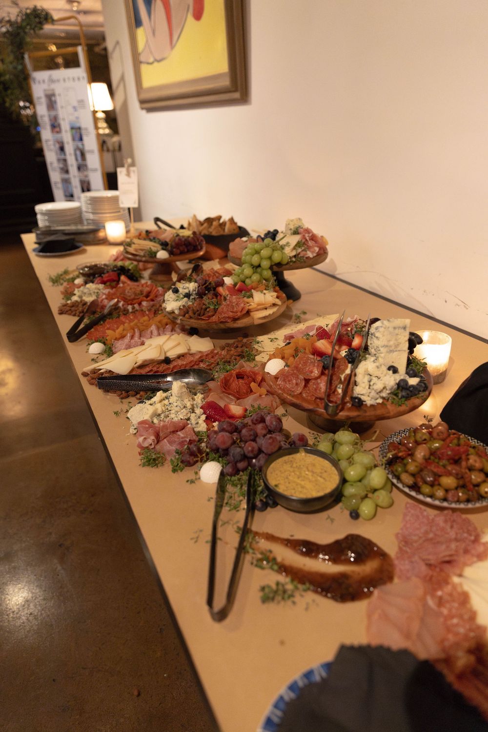 Elegant charcuterie board spread across a table featuring meats, cheeses, fruits and dips arranged on wooden serving platters.