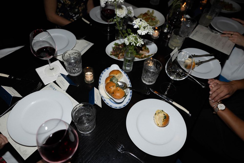 Overhead view of multiple dinner plates and wine glasses on a dark table at an elegant restaurant setting.