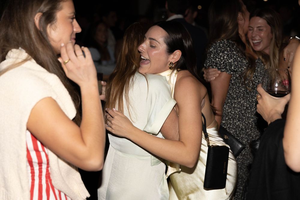 A lively crowd socializing and laughing together at a dark indoor venue or party.