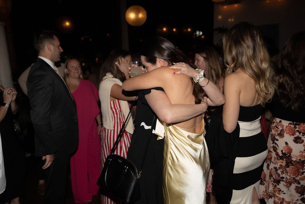 Guests dancing and mingling at a dimly lit evening party or reception.