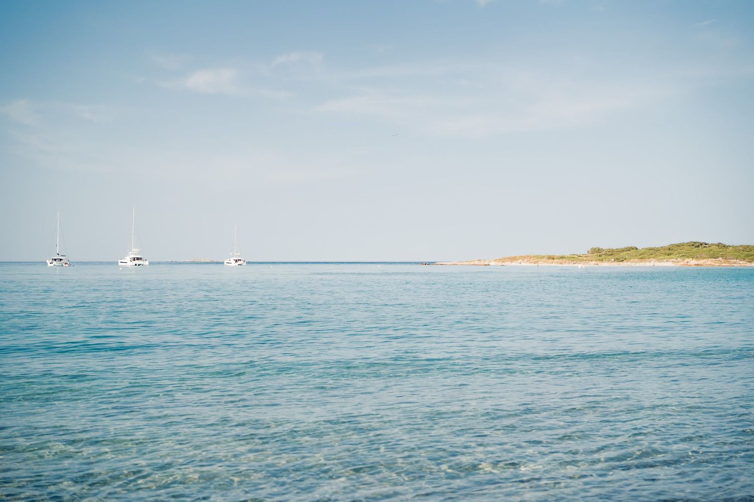 plage de piantarella à bonifacio avec eau translucide et grand ciel bleu, et bateaux en arrière-plan