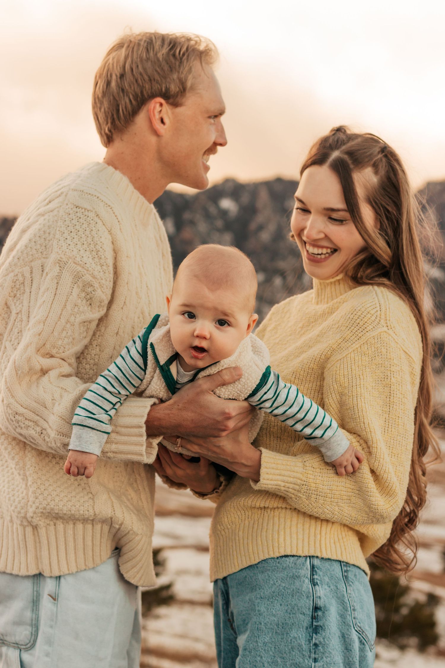 A family wearing cream sweaters shares tender moments with their baby in a series of connected|Best Family Photo Location with Mountain View