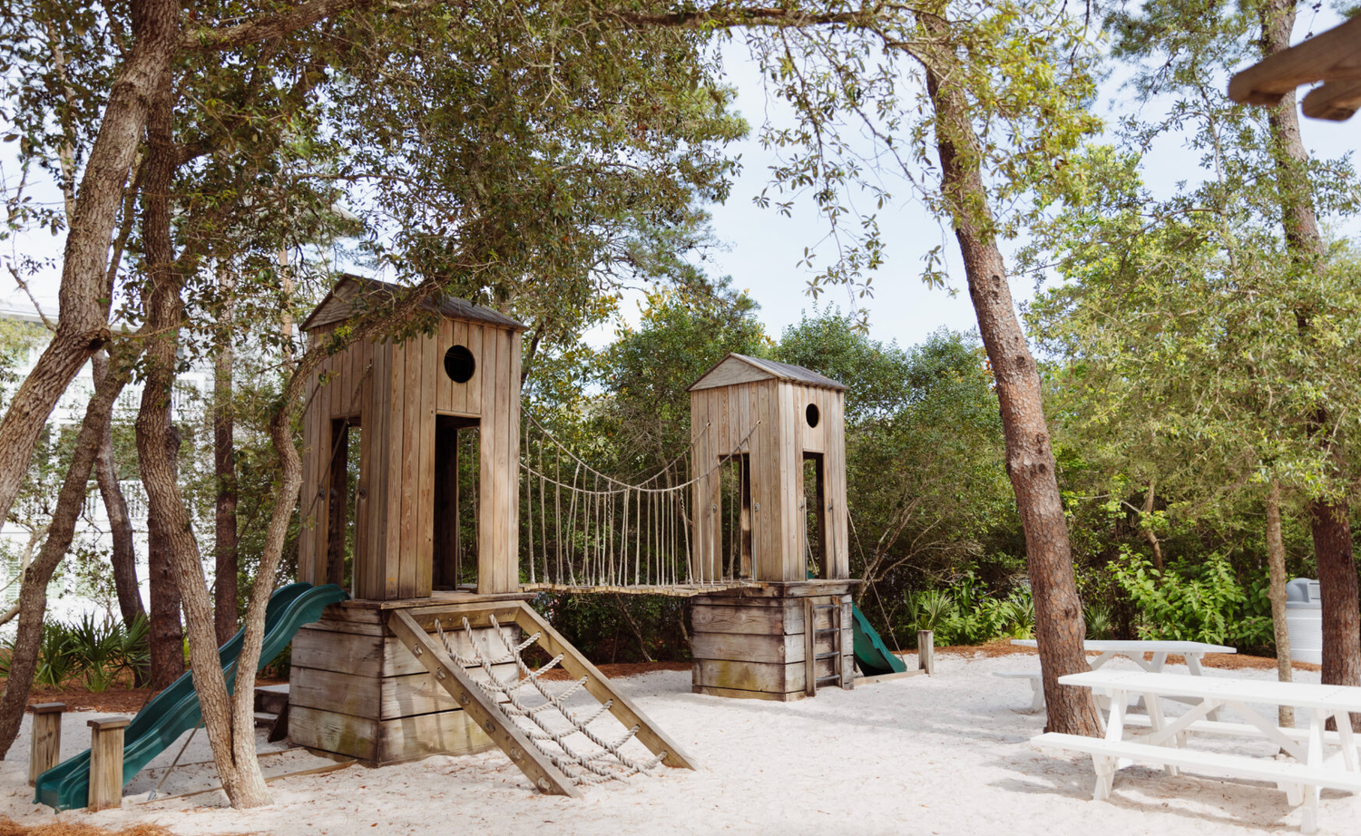 A panoramic view of rustic wooden structures nestled among pine trees at a campground or nature retreat.